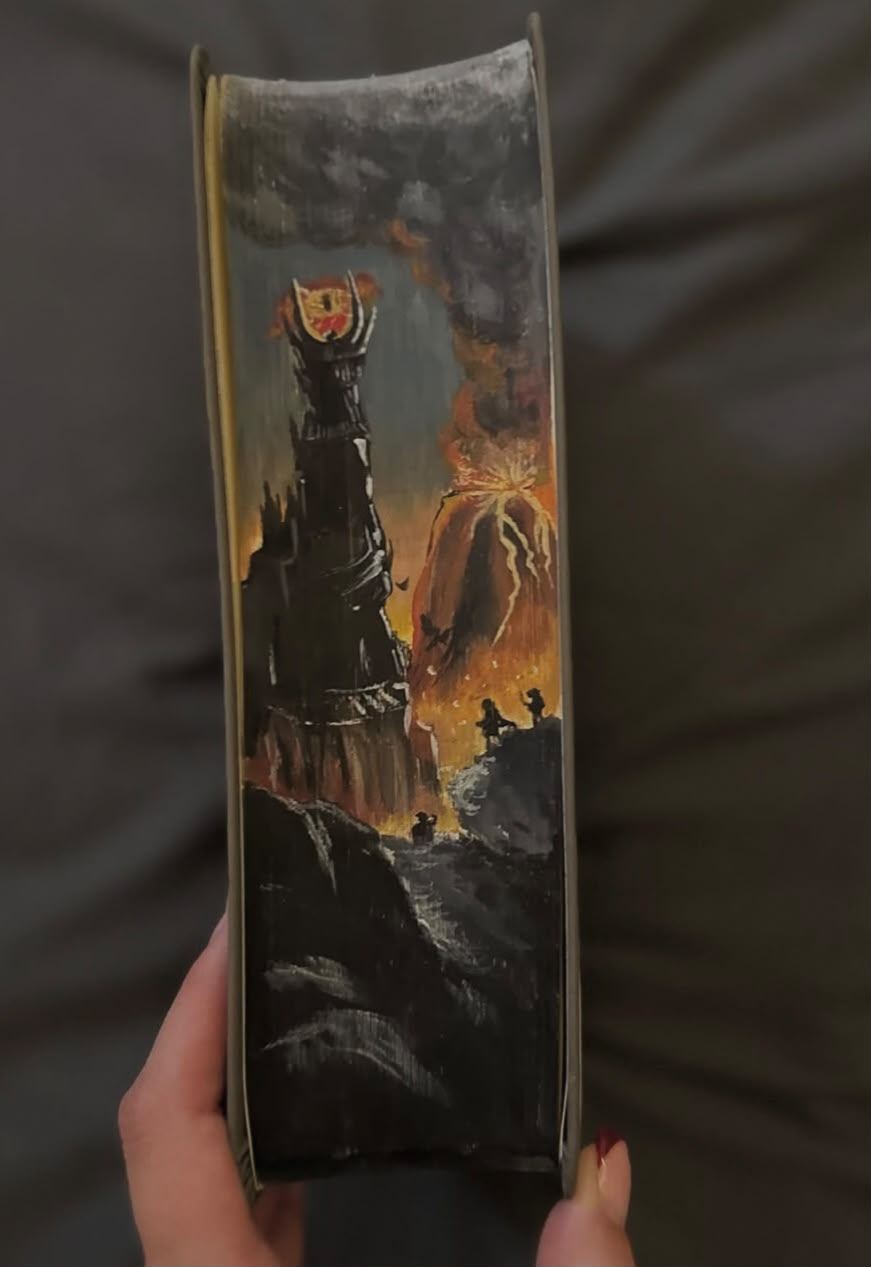 Fore-edge painting of Barad-dûr crowned by the Eye of Sauron beside an erupting Mount Doom, with Frodo and Sam on a rock in the foreground.