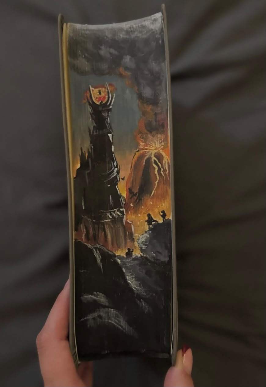 Fore-edge painting of Barad-dûr crowned by the Eye of Sauron beside an erupting Mount Doom, with Frodo and Sam on a rock in the foreground.