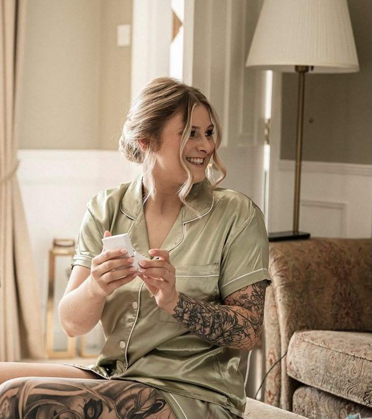 Maisie Jayne smiling, sitting in a sunlit room in a sage green shirt.