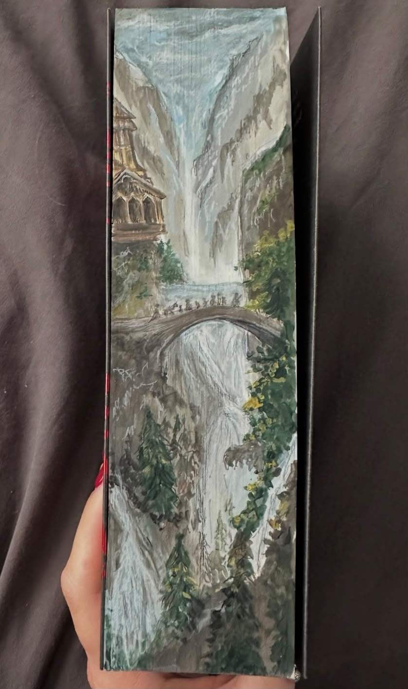 Tall fore-edge painting of Rivendell, with its waterfalls, an elven house in the cliffs and the Fellowship crossing a stone bridge.